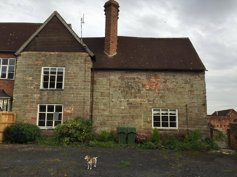 Before restoration, close view of the listed farmhouse gable showing open-jointed sandstone, historic brick infill patching and failing window frames