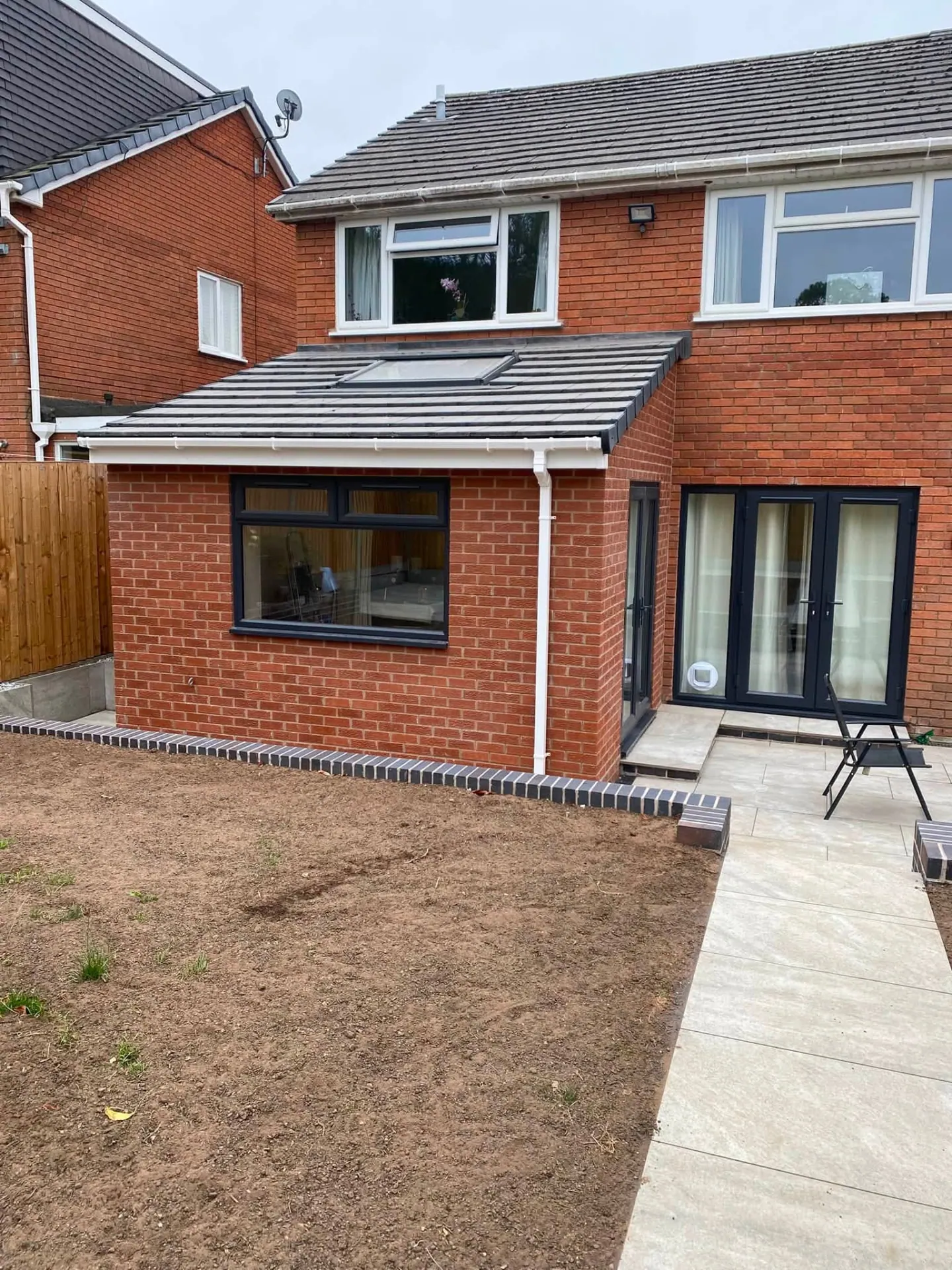 Completed rear lounge extension in Worcestershire by JRC Developers, red brick single-storey extension with grey tiled roof, rooflight, anthracite window and porcelain patio