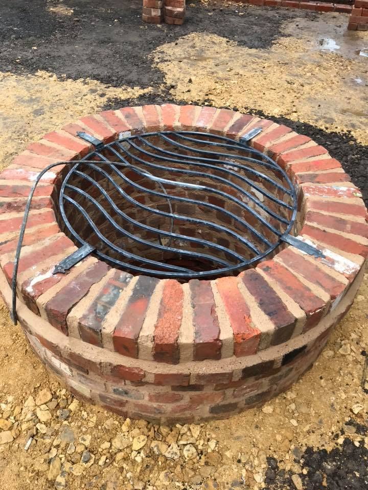 Rebuilt well head at the listed farmhouse, circular reclaimed brick surround with radial soldier-course cope and a bespoke curved steel safety grille