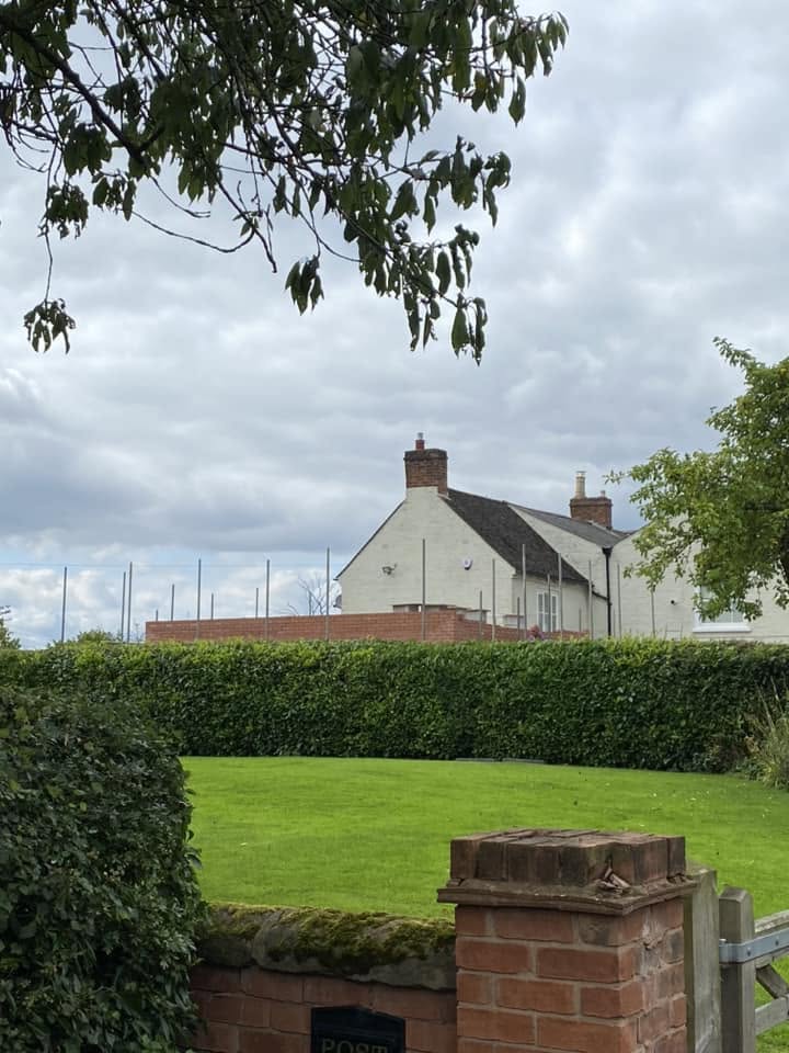 Two-storey red brick side extension under construction on a rendered period farmhouse in Worcestershire, with scaffolding and cut-roof timber trusses in place, built by JRC Developers