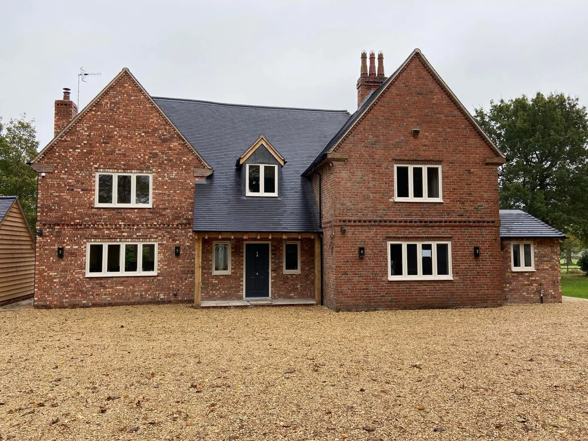 Finished front elevation of the remodelled Wootton Mead house, matching red brickwork, new porch and broad gravel drive, completed by JRC Developers